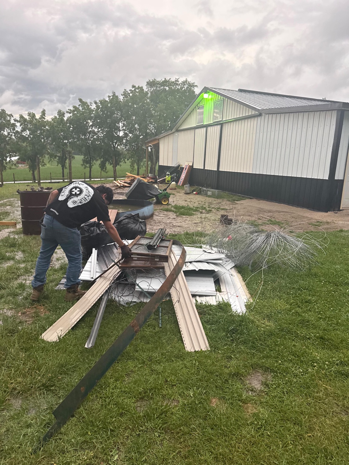 Worker clearing wood and metal debris at a barnyard